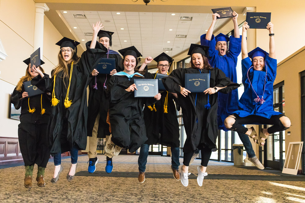 OCU Grads Jumping with Diploma